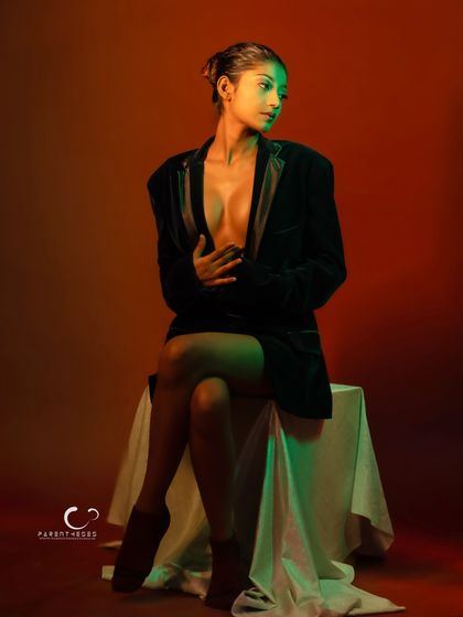 A profile view that highlights how the different colored lights interact on her skin and the velvet blazer.