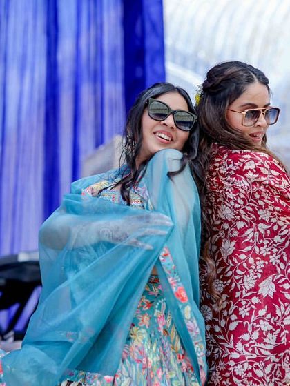 The bride and her friend posing back-to-back during their fun mehendi performance.