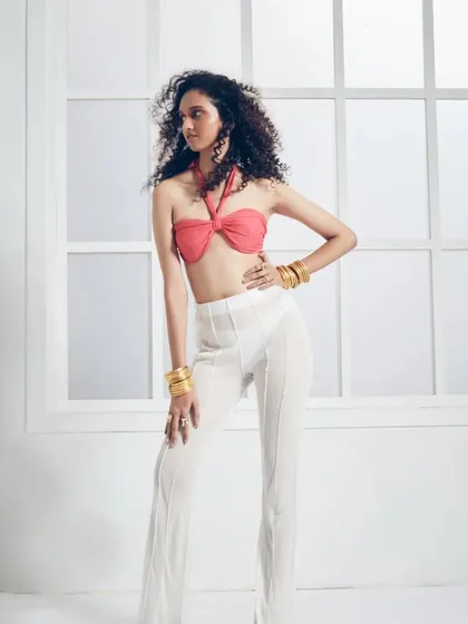 This full-length shot shows how the right hair and makeup can complete a fashion look. The voluminous curls and natural makeup enhance the model's confident pose and the overall aesthetic of the image.