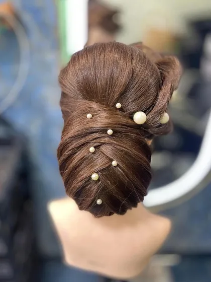 An intricate woven updo with pearl accents, created by a student. This shows their progress in mastering advanced hairstyling techniques.