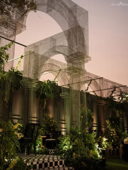 Another perspective of the mesh arches at dusk, showing their scale and the ethereal quality they bring to the outdoor space.