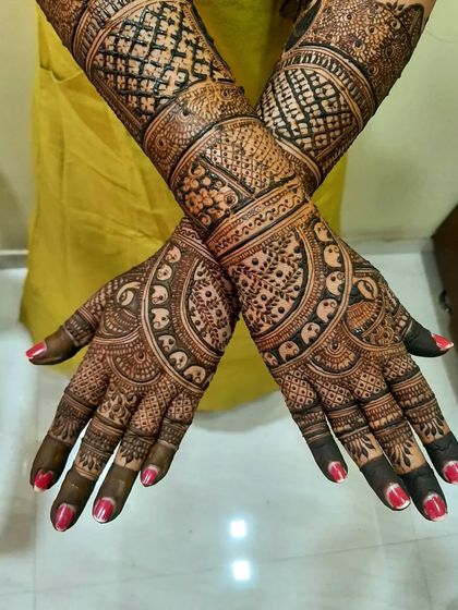 This design showcases beautiful symmetry and intricate detailing. The palms feature a circular pattern with small elephants, and the wrists have a classic checkerboard design.