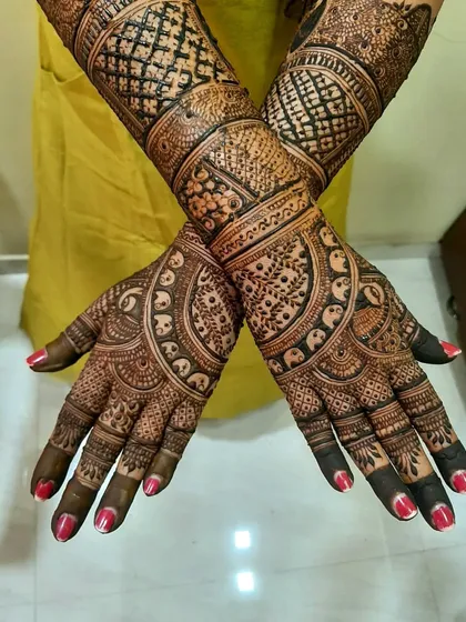 This design showcases beautiful symmetry and intricate detailing. The palms feature a circular pattern with small elephants, and the wrists have a classic checkerboard design.