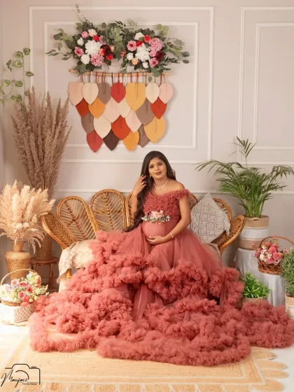 The full view of the boho setup, complete with a cane sofa, pampas grass, and unique wall hangings. This mama-to-be looks absolutely radiant in her ruffled gown.