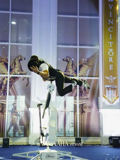 A full-body shot of the cello performer balancing on his instrument, capturing the awe-inspiring nature of the act.