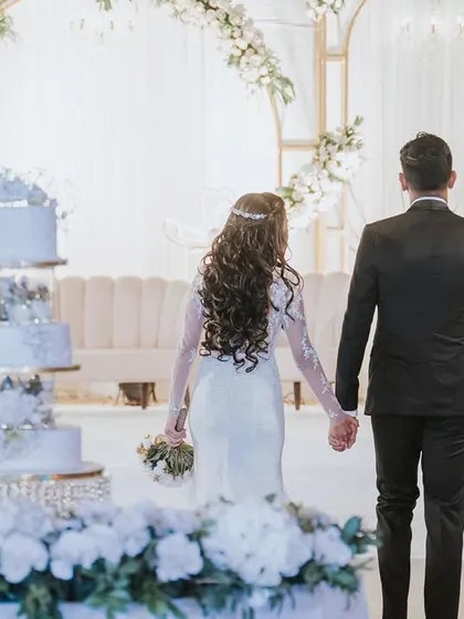 The cake cutting is a key moment. I ensure the stage and backdrop are perfect, like this elegant white and gold setup, which provides a beautiful setting for the couple and their stunning wedding cake.