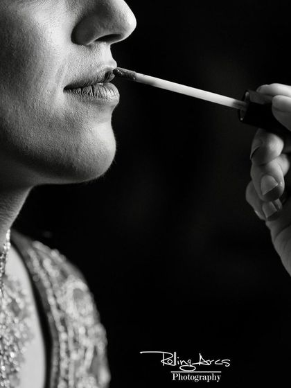 A dramatic black and white close-up of the final touch of lipstick being applied. This artistic shot focuses on the small, intimate details of the bridal preparation process.
