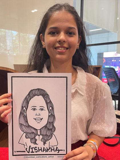 A student visiting the ITM booth at an event, happy with her new caricature.