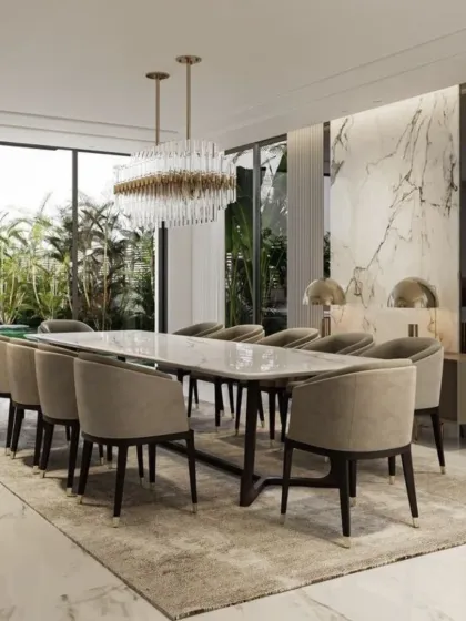 This formal dining room is designed for hosting memorable gatherings. It features a large marble-topped table that seats twelve, surrounded by comfortable upholstered chairs. The space is anchored by a stunning crystal chandelier and a marble accent wall, with large windows providing ample natural light and views of the garden.