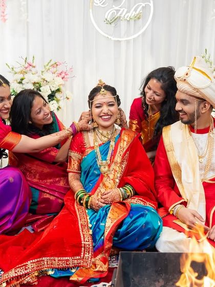 The bride's friends playfully helping her with her jewelry during the wedding ceremony.