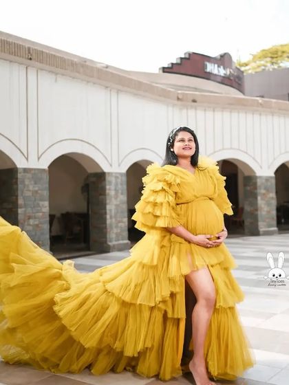This mustard yellow ruffled gown looks stunning against an architectural backdrop. The voluminous train and sleeves make it a true statement piece for any maternity photoshoot.