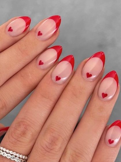 A lovely Valentine's design with almond-shaped nails, featuring a red French tip and a single, tiny heart on each nail.
