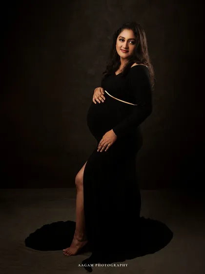 A full-length view shows the elegant silhouette of the black gown. The simplicity of the shot puts all the focus on her and her beautiful bump.