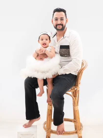 A proud father holds his daughter. This classic portrait against a minimalist background is all about the connection between a dad and his little girl.