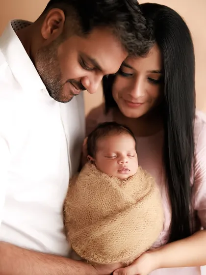 A true blessing. This close-up family portrait shows the parents' tender love as they huddle around their swaddled newborn.