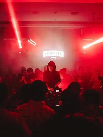 An artist at the decks, framed by red lasers and the Smirnoff sign. We partner with leading brands to create exceptional, high-quality event experiences.