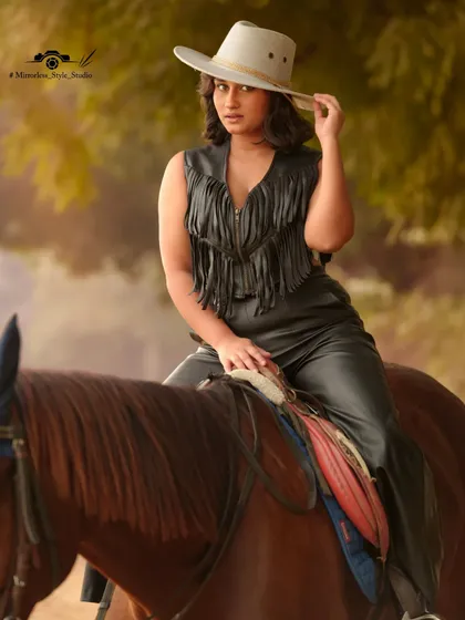 A striking portrait of a model in a fringed leather vest and hat, seated on a horse. This image demonstrates the high-fashion potential of our venue, blending equestrian style with modern trends.