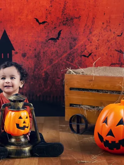 A curious little one exploring the Halloween setup with a pumpkin lantern.
