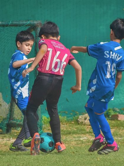 Young players from different teams compete for the ball, learning the fundamentals of the game.