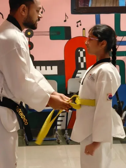 The formal tying of a new yellow belt. This ceremony marks a student's official progression to the next level in their Taekwondo training.