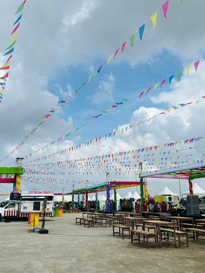 A wide shot of the outdoor festival setup at the Ola factory. We handled the complete infrastructure, including tents, seating areas, and decorative elements like bunting flags, to create a carnival-like atmosphere.