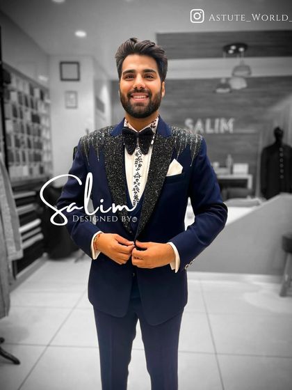 A happy client in a navy blue tuxedo with sparkling lapels and an embroidered shirt. The perfect fit and custom details come together to create a look of pure confidence.