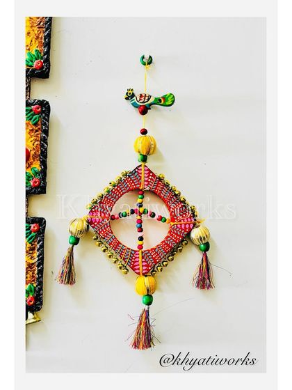 Celebrate the kite season with this handcrafted wall art. It's made on a wooden frame and decorated with ghungroos, beads, and playful tassels to capture the festive spirit.