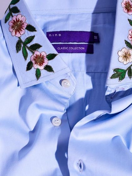 We bring a touch of nature to our formal shirts. This light blue shirt features delicate floral embroidery on the collar, adding a soft, classic appeal.