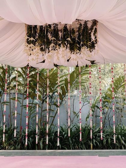 A view of the mandap setup, showing the wall of greenery and hanging floral strings. This creates a beautiful, natural backdrop for the ceremony.