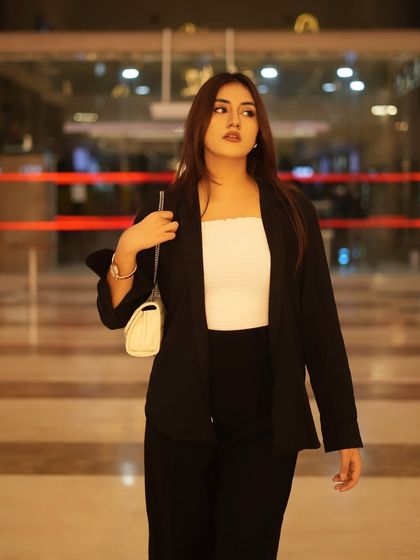 "Constantly rebranding." A classic 'boss girl' look with a black blazer, white tube top, and black trousers.