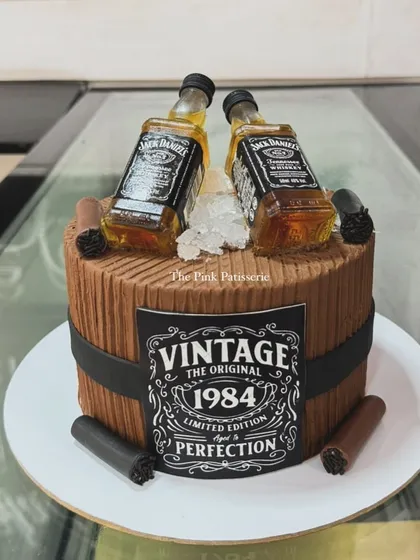 A vintage-themed Jack Daniel's barrel cake for a 1984 milestone birthday. The design includes miniature liquor bottles and edible cigars for a classic, masculine feel.