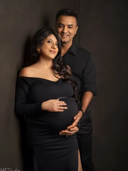 A classic and elegant pose. The couple coordinated in black, looking directly at the camera, creates a strong and timeless family portrait.