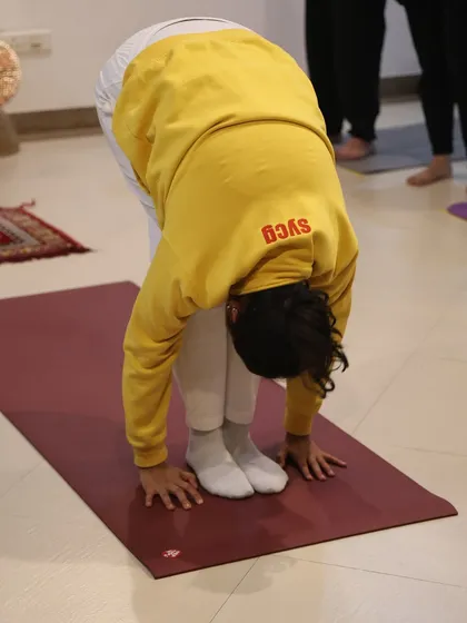 A student in Pada Hastasana, the hand to foot pose, a deep forward bend in the Surya Namaskar sequence that lengthens the spine.