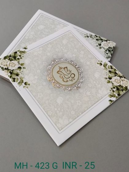 This simple white invitation is adorned with green roses and a central Ganesha emblem. It's a fresh and elegant design for a blessed wedding celebration.