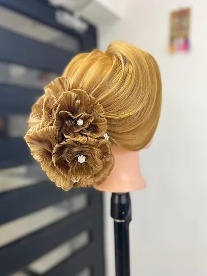 Master the art of intricate updos. This stunning floral bun, crafted entirely from hair, is an example of the advanced sculpting and design techniques you will learn in our specialized hairstyling courses.