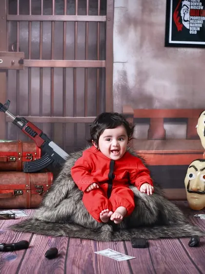 For the fans of 'Money Heist', we offer a unique and playful themed photoshoot. This creative setup, complete with iconic red jumpsuits and Dali masks, is a fun way to capture a different side of your little one's personality.