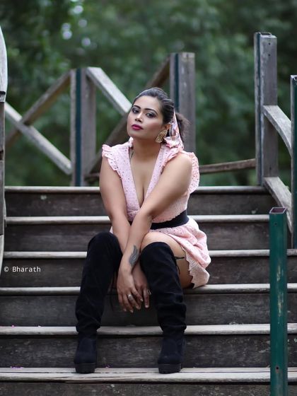 An edgy and fashionable portrait on a wooden bridge. The thigh-high boots and pose create a strong statement.