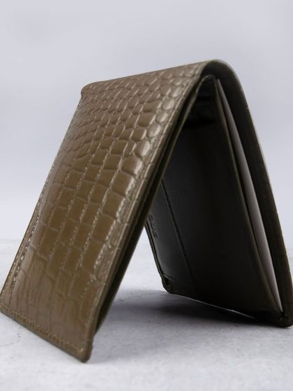 A standing shot of the olive green crocodile-textured wallet, highlighting its unique texture.