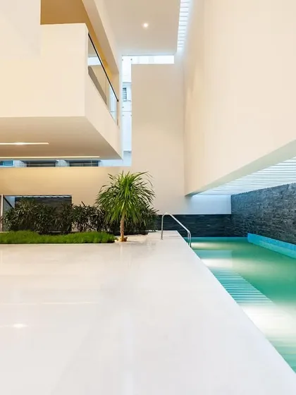 In the Neeti Residence, the swimming pool becomes a central feature of the guest level, blurring the line between inside and out. The design uses a long, linear pool flanked by a stone wall and indoor planters to create a serene, private oasis.