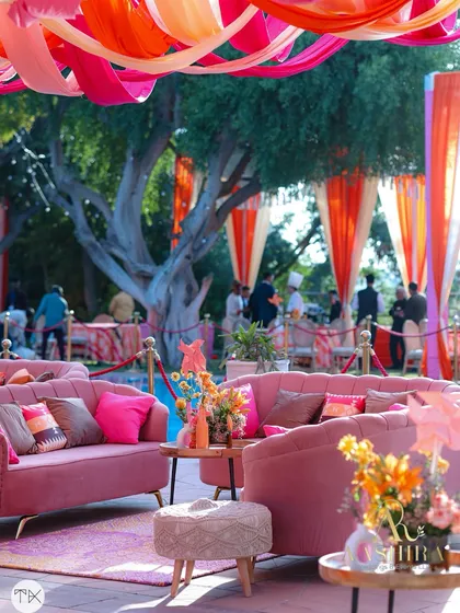 Another view of the pink lounge area, set against a backdrop of lush trees and colorful draped curtains.