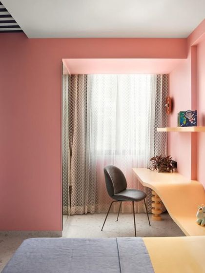 A wider view of the imaginative kids' room, showcasing the playful color blocking of pink, blue, and yellow. The custom curved desk and pebble headboard create a space that is truly one of a kind.