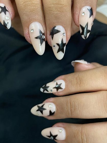 A full view of the star-studded press-on nails on my client's hands. The almond shape of the nails complements the graphic star design perfectly.