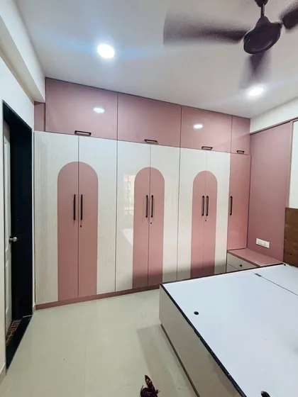 A beautiful bedroom wardrobe in a pink and white arch pattern. This floor-to-ceiling design maximizes vertical storage and adds a soft, decorative element to the room.