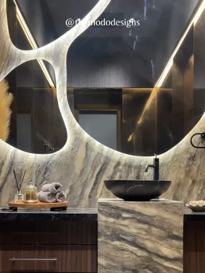 The art of luxury is in the details. In this powder room, a custom-designed, backlit mirror creates a dramatic focal point, complemented by the rich texture of marble and a modern vessel sink. It’s a testament to how thoughtful design can turn a functional space into a personal sanctuary.