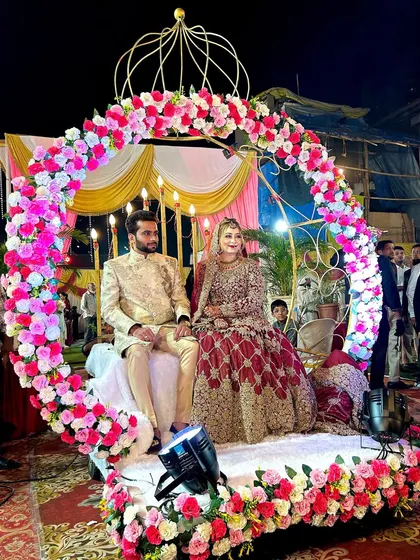 The couple seated on the Crown Entry rental, ready for their grand entrance. The floral arrangement and structure create a royal look for their special day.