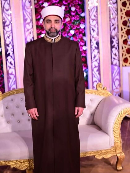 Shaykh Hashim al-Gaylani in a full-length view of his custom Overcoat Sherwani, standing with grace and poise at a formal event.