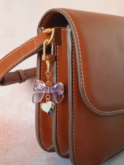 Another angle of the iridescent bow and rainbow heart bag charm, showing how it catches the light from the side.