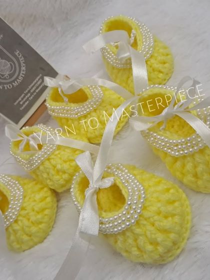 These bright yellow booties are decorated with a string of pearls and a white satin ribbon, making them a cheerful and elegant choice.