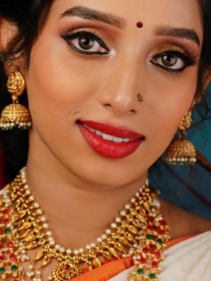 Another portrait from the same traditional jewelry shoot. This image showcases the model's pleasant expression and provides a clear view of the full necklace set against her white and orange saree, demonstrating our skill in commercial beauty photography.