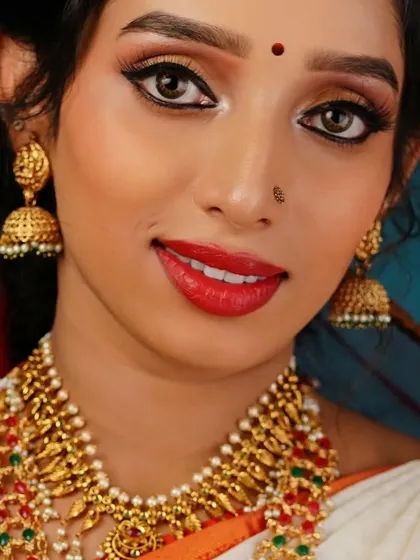 Another portrait from the same traditional jewelry shoot. This image showcases the model's pleasant expression and provides a clear view of the full necklace set against her white and orange saree, demonstrating our skill in commercial beauty photography.